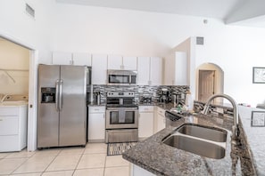 A modern kitchen with stainless steel appliances, a granite countertop, and a double sink.