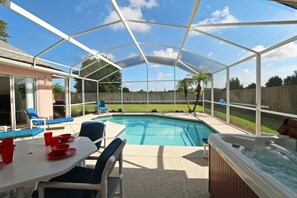 A covered outdoor area with a pool, lounge chairs, and a hot tub. - Country Feel,Private Pool,Spa, Game Room (Kissimmee)