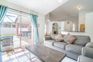 A living room with a sofa, a coffee table, and a sliding glass door leading to an outdoor area.