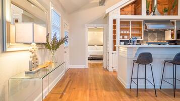 A modern kitchen with a central island, bar stools, and a dining area.