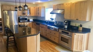 A modern kitchen with wooden cabinets, stainless steel appliances, and a central island. - Walk to the Beach, Heated Salt Water Pool, Central AC (Dennis)