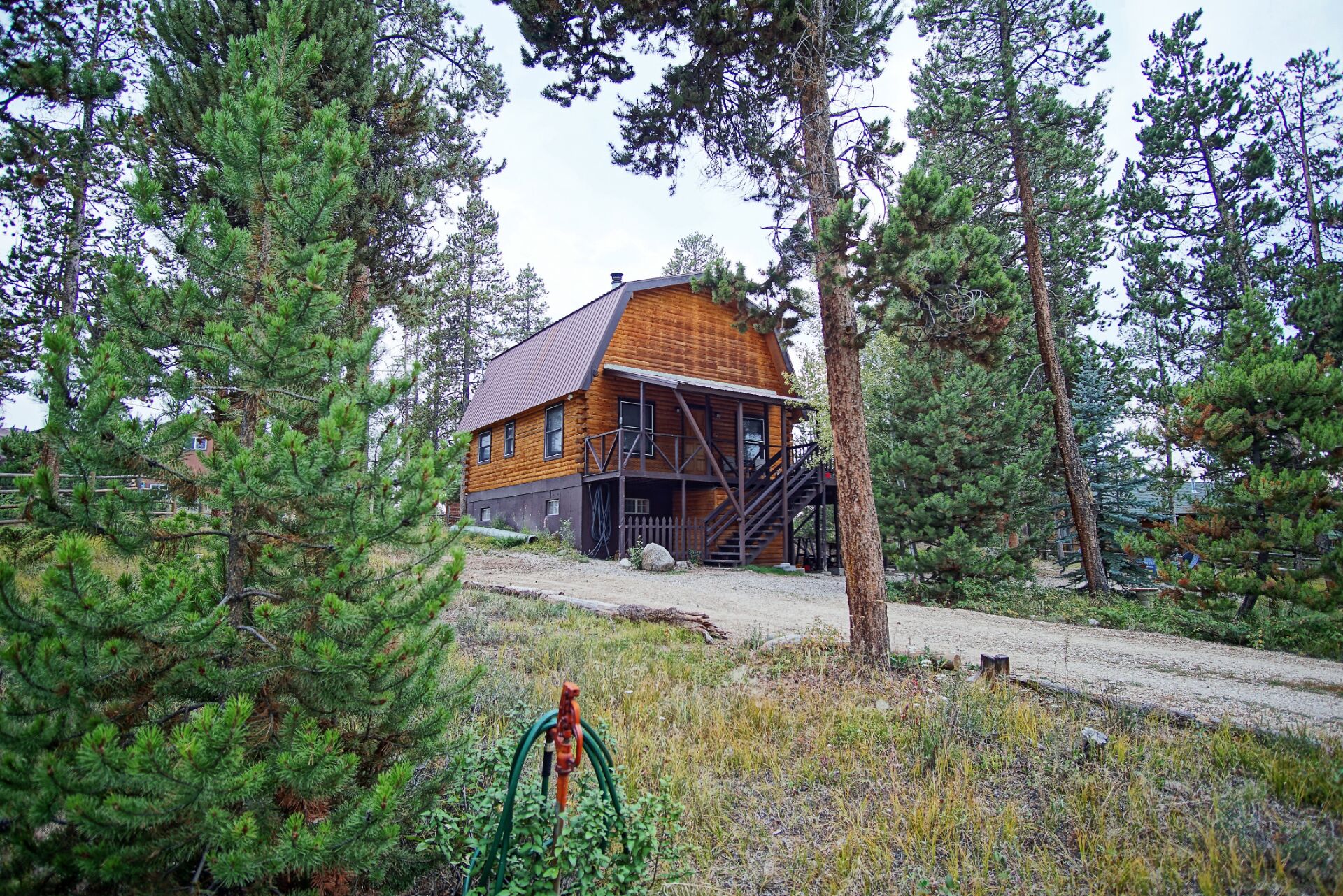 A cabin with a wooden exterior, a porch, and a staircase leading to the entrance.