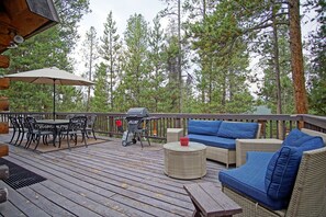A wooden deck with outdoor furniture, including a table and chairs, a sofa, and a grill.