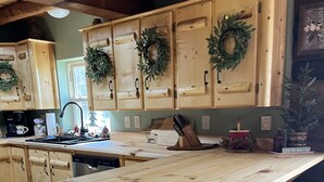 Una cocina con armarios de madera, una isla central con taburetes y una guirnalda colgante.