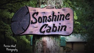 A wooden sign with the text "Sunshine Cabin" mounted on a tree.