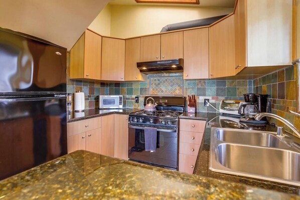 A kitchen with a stove, microwave, and sink.