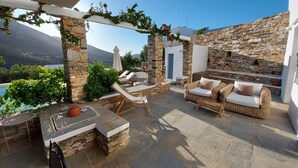 Um pátio de pedra com área de estar ao ar livre, piscina e vista para as montanhas.