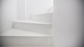 Escadas brancas e vazias sobem em um interior minimalista.
