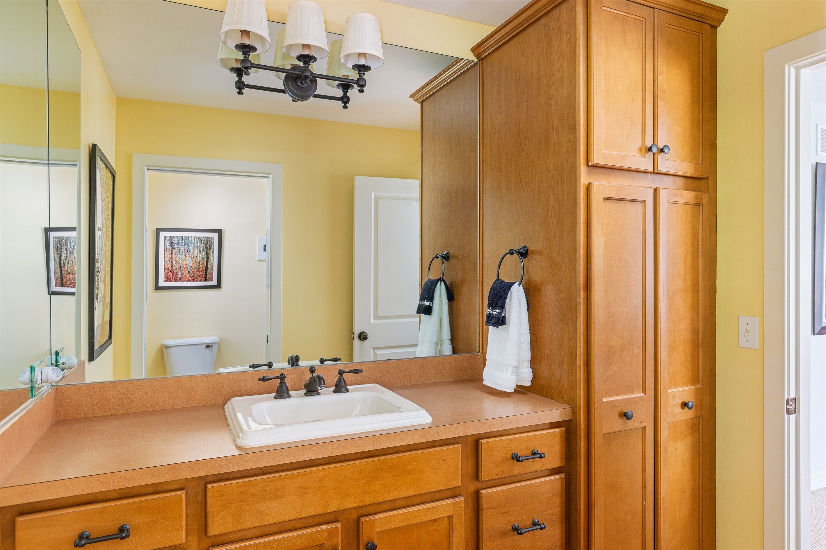 A bathroom with a wooden vanity, a large mirror, and a sink.