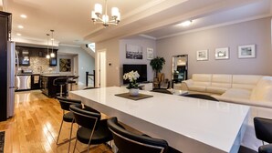 Une cuisine spacieuse dotée d’un grand îlot central, d’appareils électroménagers modernes et d’un coin repas avec une table blanche et des chaises noires.
