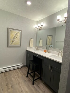 A bathroom with two sinks, a large mirror, and a framed fish artwork on the wall. - Newly Renovated Mountain Condo in Convenient Location (Whitefish)