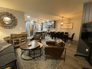 Uma sala de estar moderna com sofá, mesa de centro e área de jantar.