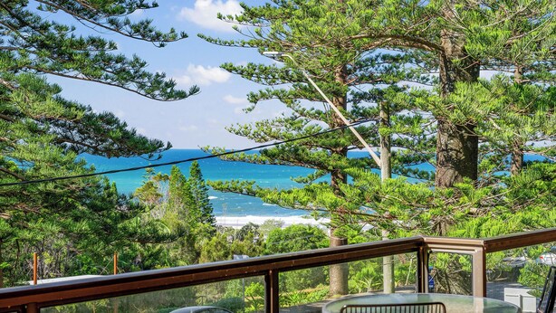 Ein Balkon mit Blick auf das Meer, umgeben von Bäumen.