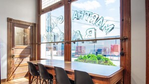 A wooden table with four chairs in a room with large windows.