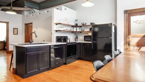 A modern kitchen with black appliances, wooden flooring, and a dining area with a wooden table and chairs.