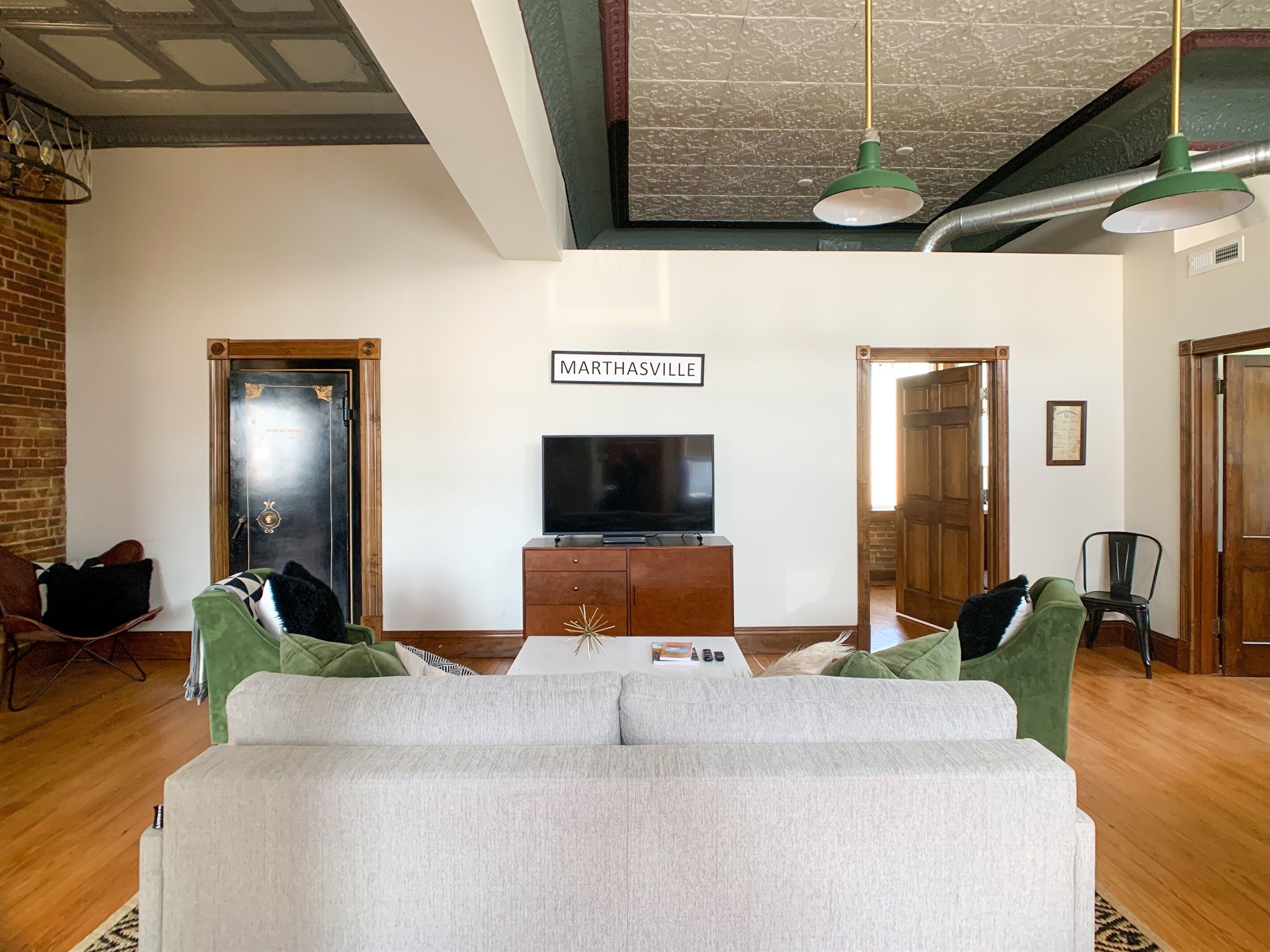 A living room with a sofa, a television on a wooden cabinet, and a sign that reads 'Marthasville'.