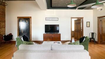 A living room with a sofa, a television on a wooden cabinet, and a sign that reads 'Marthasville'.