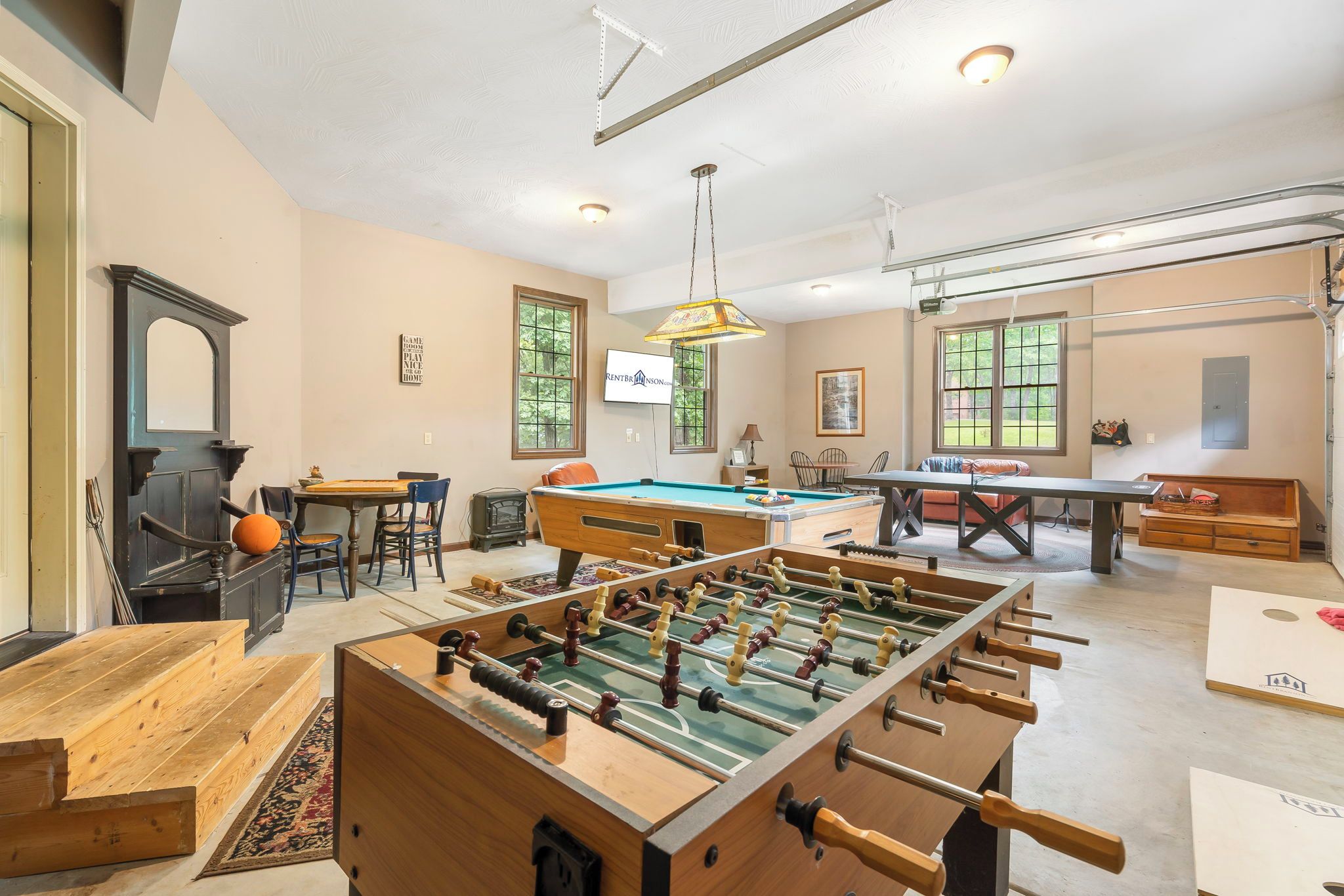 A spacious living room with a foosball table, a pool table, and a television mounted on the wall.