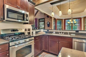 A kitchen with stainless steel appliances, wooden cabinets, a granite countertop, and pendant lighting. - Secluded 40 Acres Near Table Rock, Stunning Views, Games, Community Pool & Car Charger (Blue Eye)