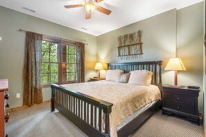 A bedroom with a bed, two bedside lamps, a nightstand, a ceiling fan, and a window with curtains. - Secluded 40 Acres Near Table Rock, Stunning Views, Games, Community Pool & Car Charger (Blue Eye)