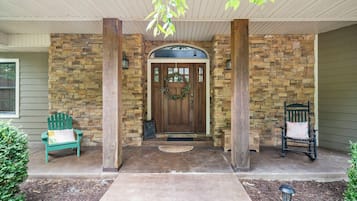 A stone-clad entrance with a wooden door, a bench, and a chair outside.