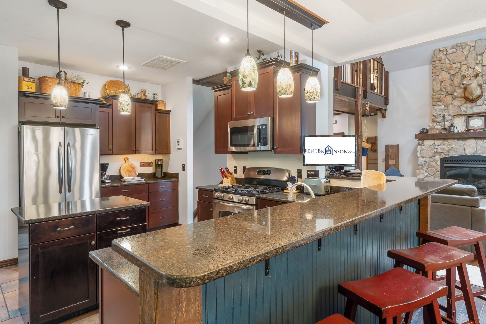 A modern kitchen with a central island, stainless steel appliances, and pendant lighting.