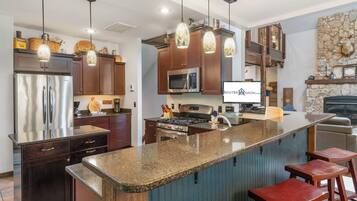 A modern kitchen with a central island, stainless steel appliances, and pendant lighting.