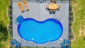 A rectangular swimming pool with a wooden deck surrounding it, featuring lounge chairs and a table. - Secluded 40 Acres Near Table Rock, Stunning Views, Games, Community Pool & Car Charger (Blue Eye)
