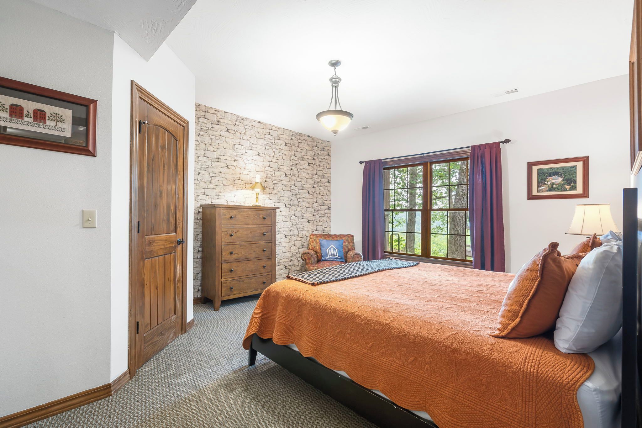 A bedroom with a bed, dresser, and a stone wall.