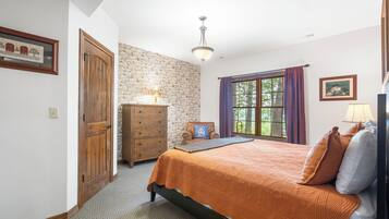 A bedroom with a bed, dresser, and a stone wall.
