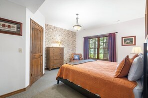 A bedroom with a bed, dresser, and a stone wall. - Secluded 40 Acres Near Table Rock, Stunning Views, Games, Community Pool & Car Charger (Blue Eye)