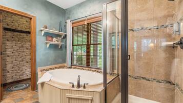 A bathroom with a freestanding bathtub, a glass shower enclosure, and a stone wall.