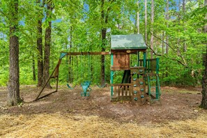 A wooden play structure with a swing set and climbing elements in a forested area. - Secluded 40 Acres Near Table Rock, Stunning Views, Games, Community Pool & Car Charger (Blue Eye)