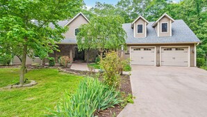 A two-story house with a garage, a front yard with a tree, and a well-maintained lawn. - Secluded 40 Acres Near Table Rock, Stunning Views, Games, Community Pool & Car Charger (Blue Eye)