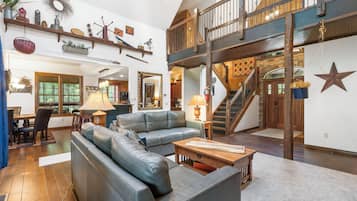 A spacious living area with a leather sofa, wooden coffee table, and a staircase leading to an upper level.