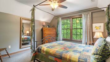 A bedroom with a bed, a dresser, a mirror, a window with curtains, and a ceiling fan.