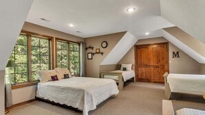 A bedroom with a large bed, two smaller beds, a wooden wardrobe, and a window with a view of trees. - Secluded 40 Acres Near Table Rock, Stunning Views, Games, Community Pool & Car Charger (Blue Eye)