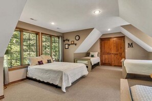A bedroom with a large bed, two smaller beds, a wooden wardrobe, and a window with a view of trees. - Secluded 40 Acres Near Table Rock, Stunning Views, Games, Community Pool & Car Charger (Blue Eye)