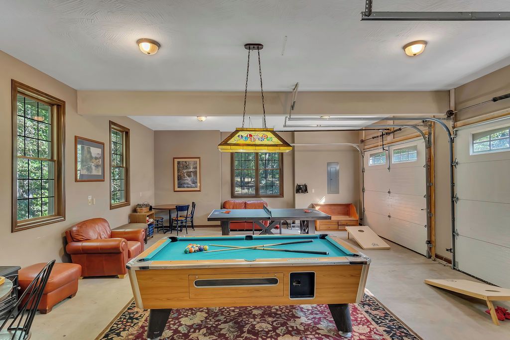 A pool table in a room with a ceiling light, a sofa, and a table with chairs.