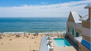 A beach view with a pool area and a building with a sloped roof.