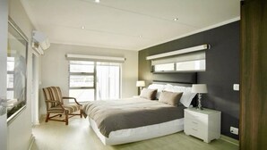 Una camera da letto con un letto, comodini, una sedia e una finestra.