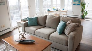 Una sala de estar con un sofá color beige, una mesa de centro de madera y un comedor al fondo.
