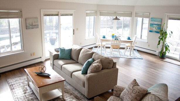 Amplia sala de estar con un sofá color beige, una mesa de centro de madera y un comedor con mesa y sillas.