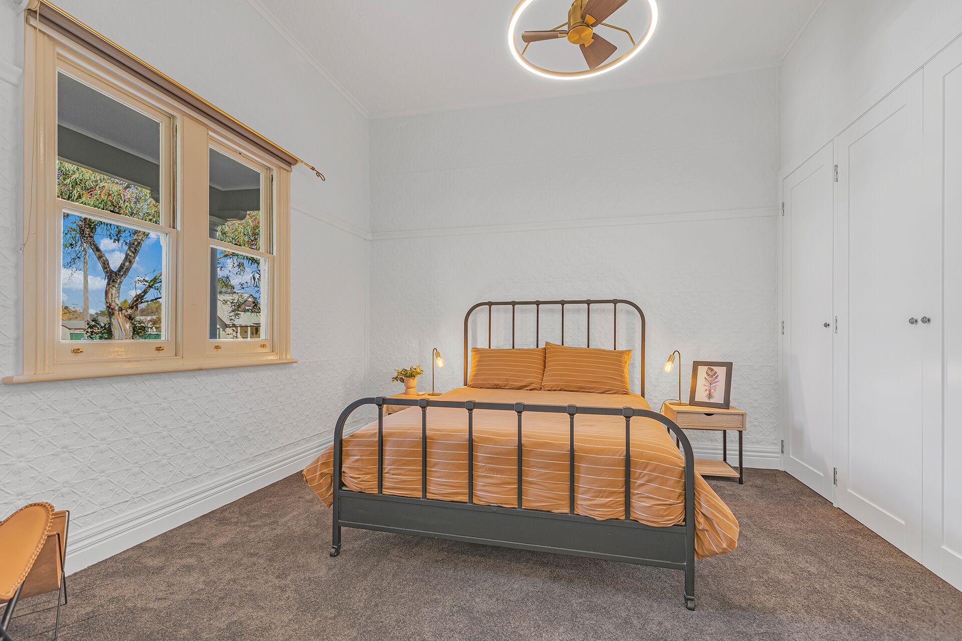Ein Schlafzimmer mit Bett, Fenster mit Aussicht, Nachttisch und Kleiderschrank.