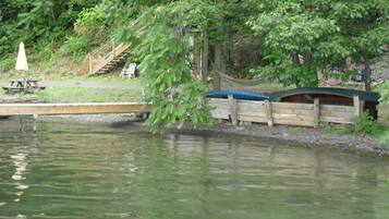 Un pont de fusta s'enduu cap a un llac tranquil, envoltat de vegetació exuberant i un petit pont de fusta.