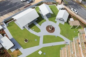 An aerial view of a modern building with a central courtyard, surrounded by green lawns and pathways.