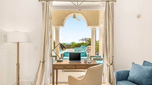 Ein Zimmer mit Schreibtisch, Stuhl und Blick auf ein Freibad.