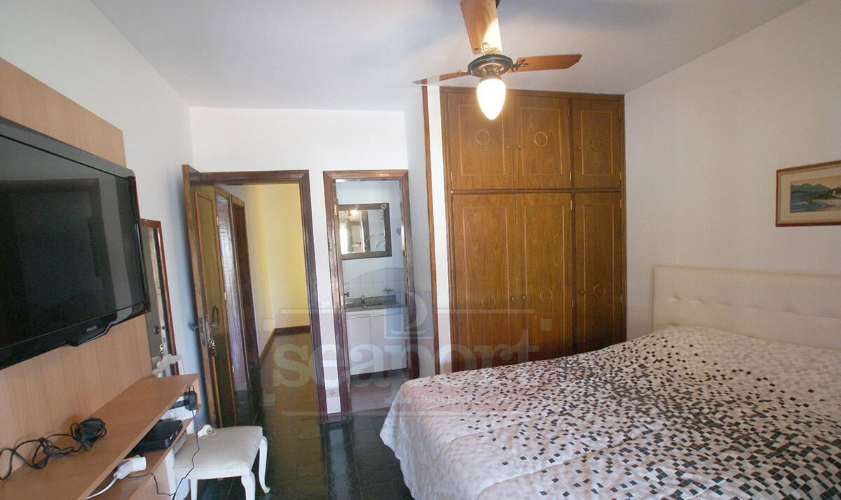 A bedroom with a bed, a TV, a ceiling fan, and a wardrobe.