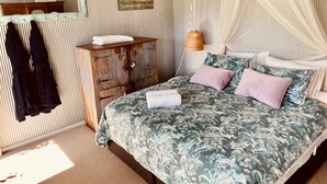 Een slaapkamer met een bed, een houten garderobe, een spiegel en een hemelbed.