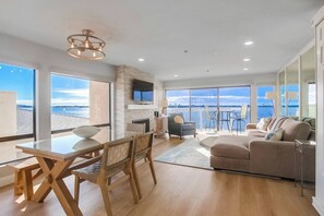 A modern living room with a large window, a dining area, and a sofa.